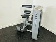 Matrix G7 Series Commercial Back Extension Machine in a gym setting, featuring a weight stack, contoured back pad, and multi-position foot placement.